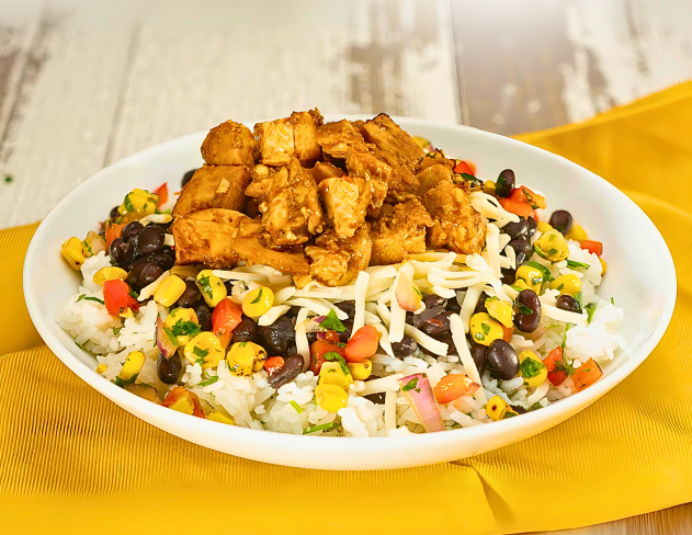 A bowl of rice topped with chicken and toppings.